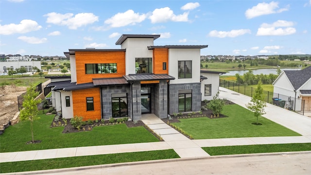 contemporary home featuring a water view and a front lawn