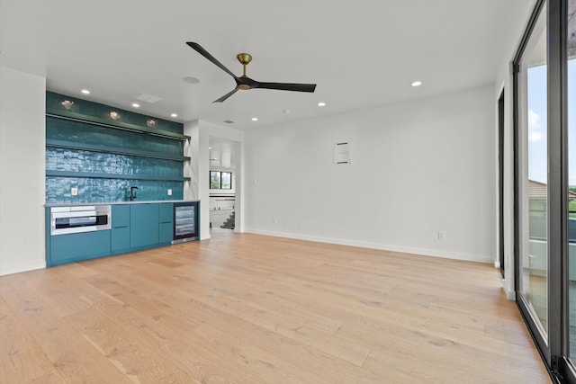 unfurnished living room with beverage cooler, ceiling fan, and light hardwood / wood-style flooring