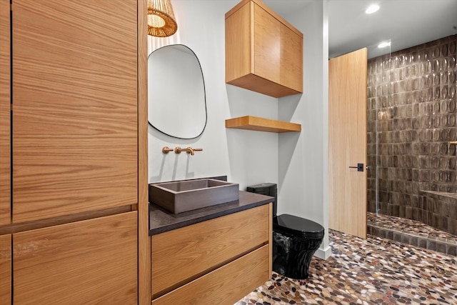 bathroom featuring a tile shower, vanity, and tile floors