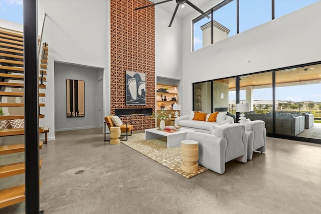 living room featuring a high ceiling, ceiling fan, and concrete floors