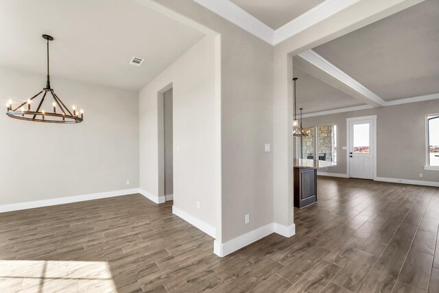 empty room featuring beam ceiling, crown molding, dark wood-type flooring, and an inviting chandelier