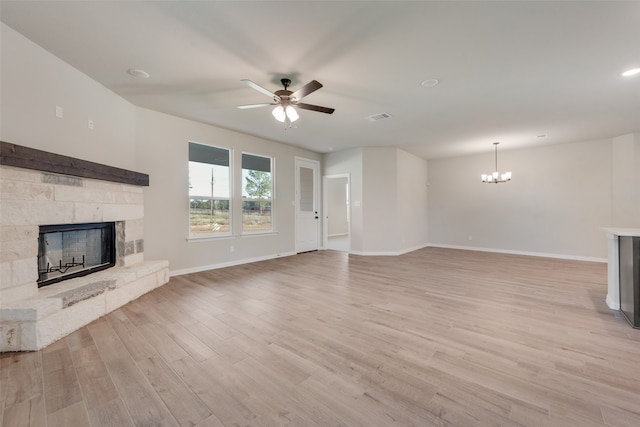 unfurnished living room with a fireplace, ceiling fan with notable chandelier, and light wood-type flooring