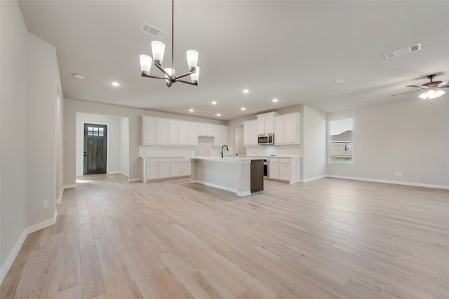 kitchen with an island with sink, ceiling fan with notable chandelier, hanging light fixtures, white cabinetry, and light hardwood / wood-style flooring