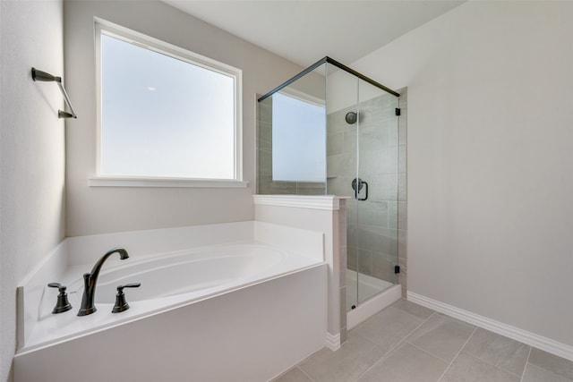 bathroom with plus walk in shower, a healthy amount of sunlight, and tile patterned flooring