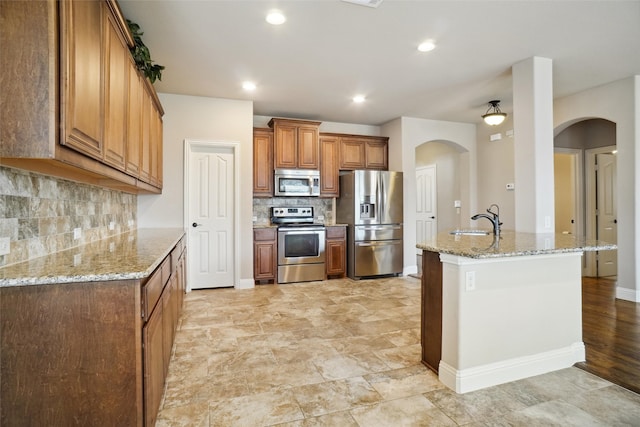 kitchen with light tile flooring, stainless steel appliances, sink, light stone counters, and tasteful backsplash