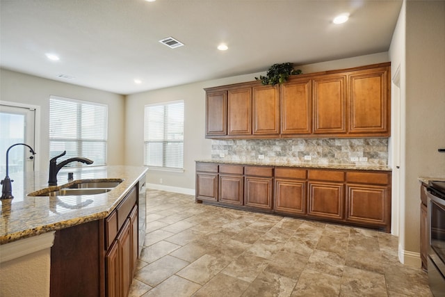 kitchen with appliances with stainless steel finishes, tasteful backsplash, light stone countertops, and light tile floors