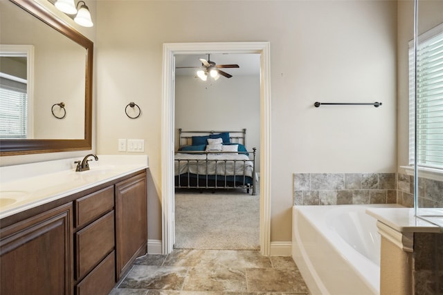 bathroom featuring tile flooring, double sink vanity, ceiling fan, a washtub, and plenty of natural light