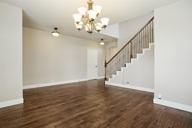 spare room with dark wood-type flooring and a notable chandelier