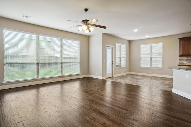 unfurnished living room with a wealth of natural light, wood-type flooring, and ceiling fan