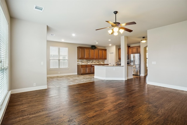 unfurnished living room featuring hardwood / wood-style floors, sink, and ceiling fan