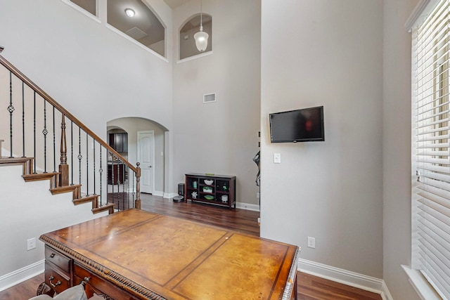 dining room with dark hardwood / wood-style floors and a towering ceiling