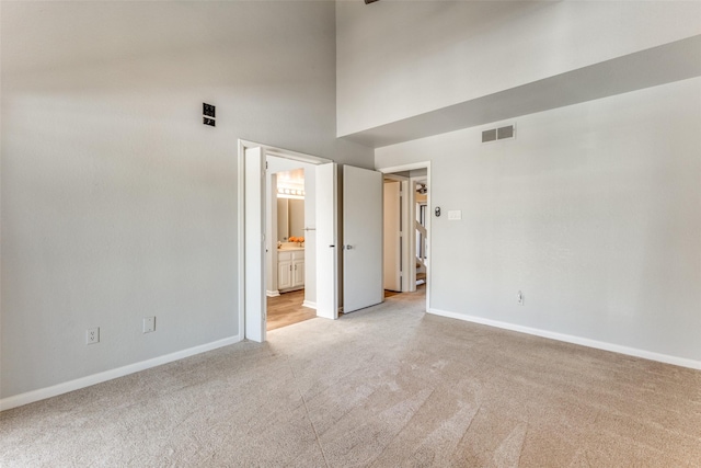 spare room featuring a high ceiling and light carpet