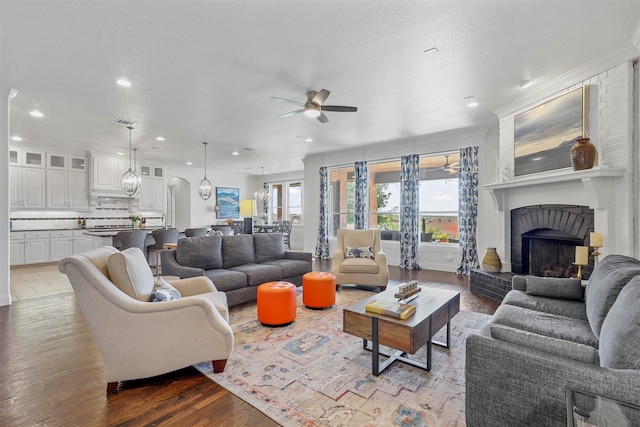 living room with dark wood-type flooring, ceiling fan, a textured ceiling, and crown molding