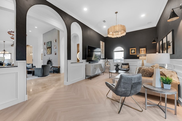 living room featuring crown molding, a notable chandelier, and light parquet flooring