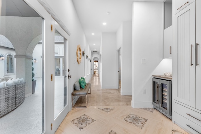 corridor featuring a wealth of natural light, light tile floors, and beverage cooler