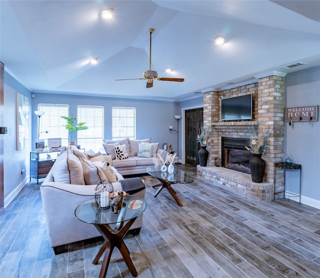 living room with a fireplace, crown molding, vaulted ceiling, hardwood / wood-style flooring, and ceiling fan