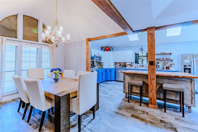 dining room with high vaulted ceiling, beam ceiling, an inviting chandelier, and light wood-type flooring