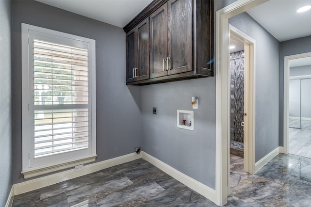 washroom featuring hookup for an electric dryer, dark tile flooring, a wealth of natural light, and cabinets