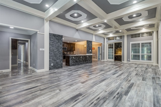 unfurnished living room featuring coffered ceiling, sink, beamed ceiling, and wood-type flooring