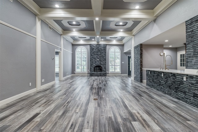 unfurnished living room with a high ceiling, coffered ceiling, a fireplace, and hardwood / wood-style flooring