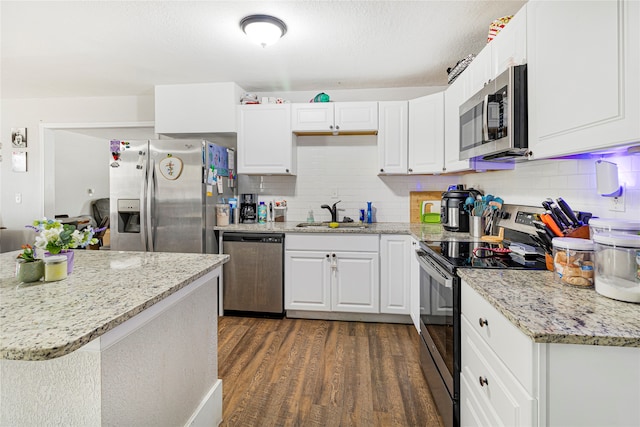 kitchen with appliances with stainless steel finishes, white cabinets, sink, tasteful backsplash, and dark hardwood / wood-style flooring