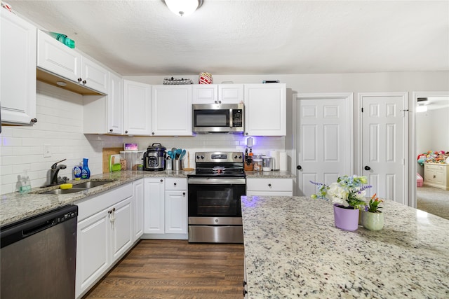 kitchen featuring appliances with stainless steel finishes, dark hardwood / wood-style floors, sink, and light stone counters