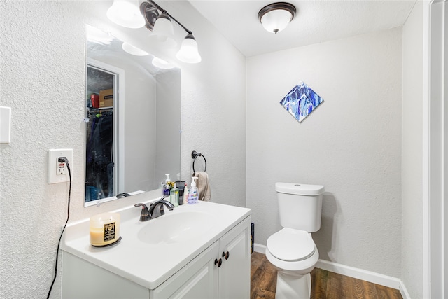 bathroom with wood-type flooring, toilet, and vanity with extensive cabinet space