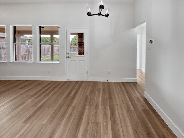 spare room featuring a chandelier and light hardwood / wood-style floors