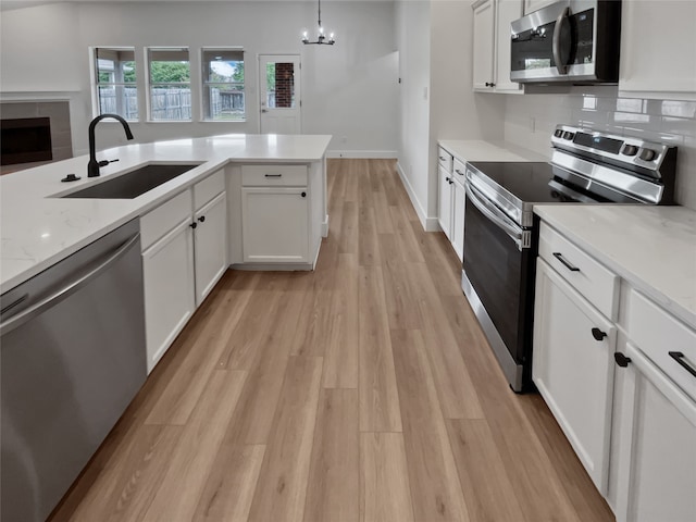 kitchen featuring stainless steel appliances, sink, white cabinetry, and light hardwood / wood-style floors