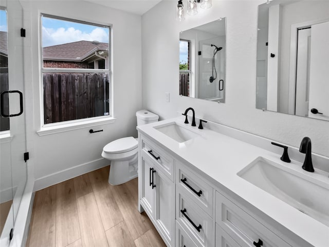 bathroom with dual vanity, plenty of natural light, toilet, and wood-type flooring