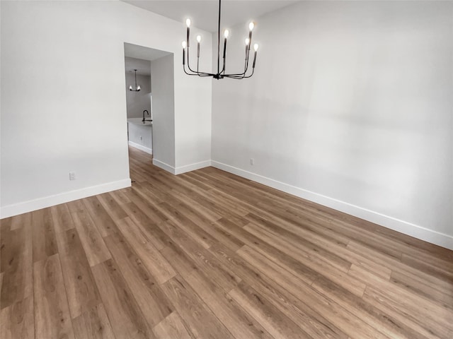 unfurnished dining area featuring a notable chandelier and hardwood / wood-style floors