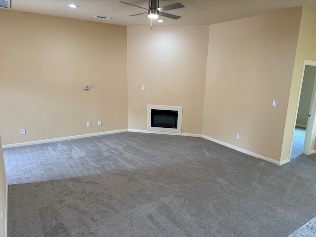 unfurnished living room with ceiling fan and dark colored carpet