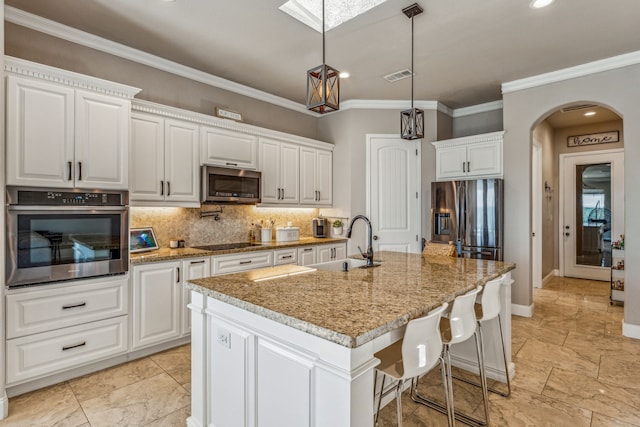 kitchen with white cabinets, a center island with sink, appliances with stainless steel finishes, and light tile floors