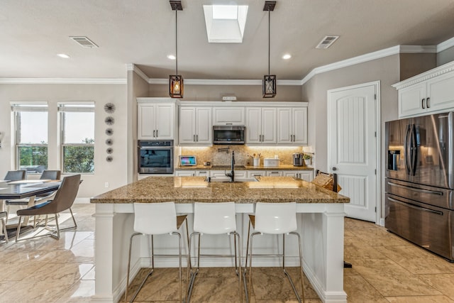 kitchen featuring hanging light fixtures, white cabinets, a skylight, and appliances with stainless steel finishes