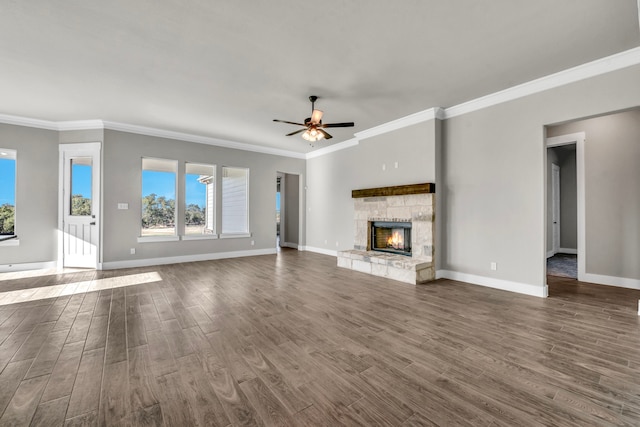 unfurnished living room featuring dark wood-type flooring, ceiling fan, a stone fireplace, and crown molding