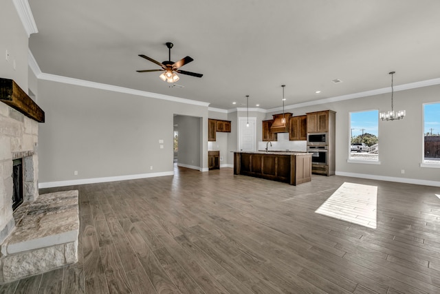 unfurnished living room with a stone fireplace, ceiling fan with notable chandelier, dark hardwood / wood-style floors, and crown molding