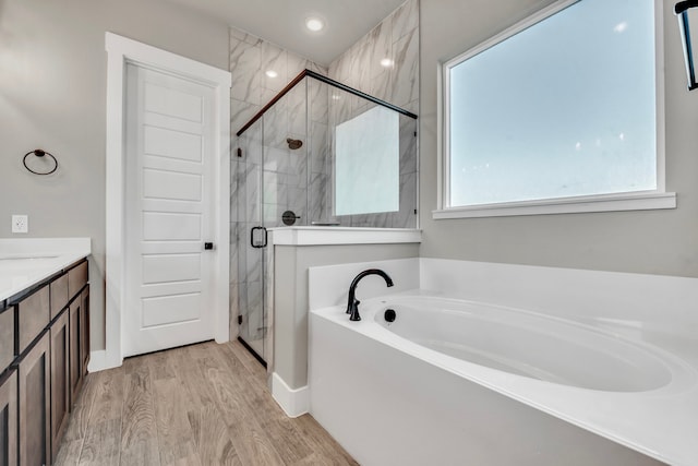 bathroom featuring hardwood / wood-style flooring, vanity, and shower with separate bathtub