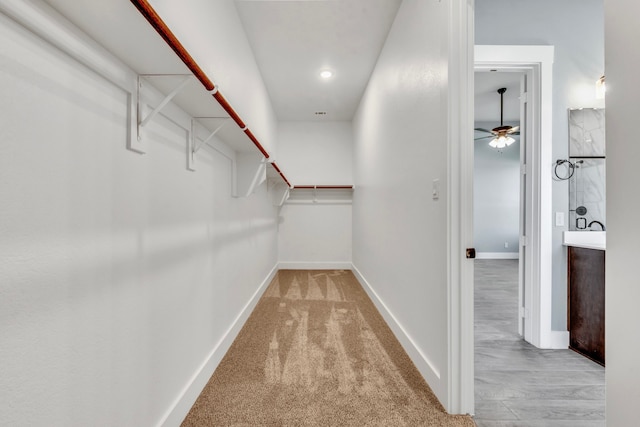 spacious closet featuring light colored carpet and ceiling fan