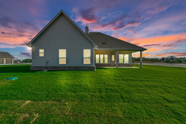 back house at dusk featuring a yard