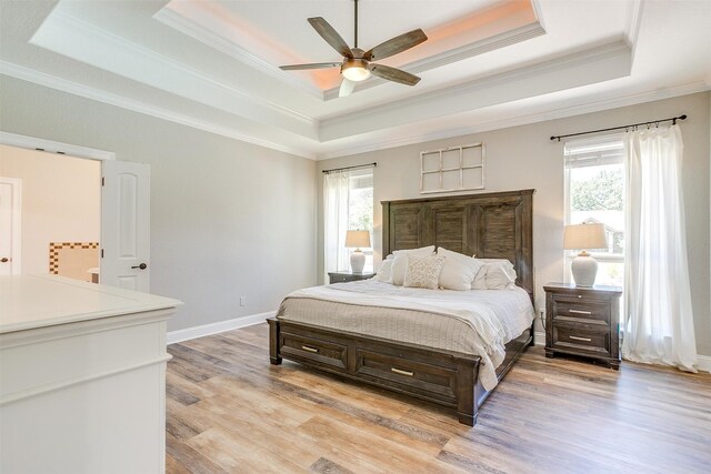 bedroom with ornamental molding, a tray ceiling, light hardwood / wood-style floors, and ceiling fan