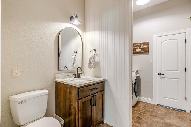 bathroom with vanity, tile patterned floors, toilet, and washer / dryer