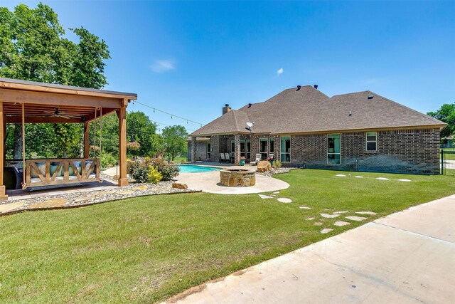 rear view of property with a yard, ceiling fan, and a patio area