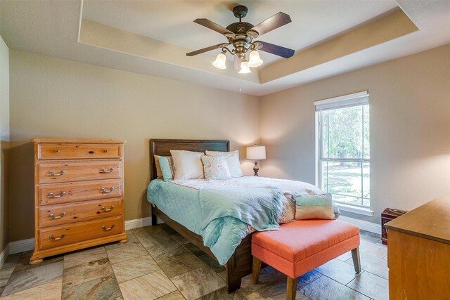 bedroom featuring a raised ceiling and multiple windows