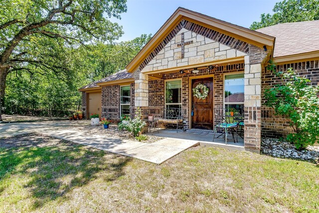 entrance to property with a lawn and a patio area