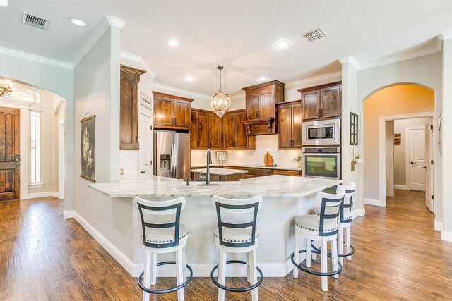 kitchen featuring pendant lighting, appliances with stainless steel finishes, dark wood-type flooring, and kitchen peninsula