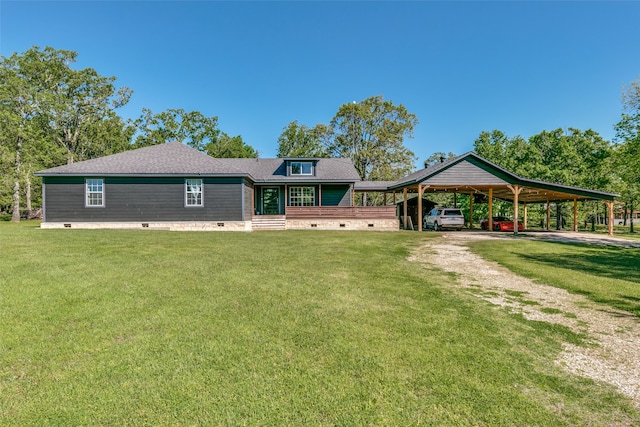 rear view of property with a shingled roof, a lawn, crawl space, an attached carport, and driveway