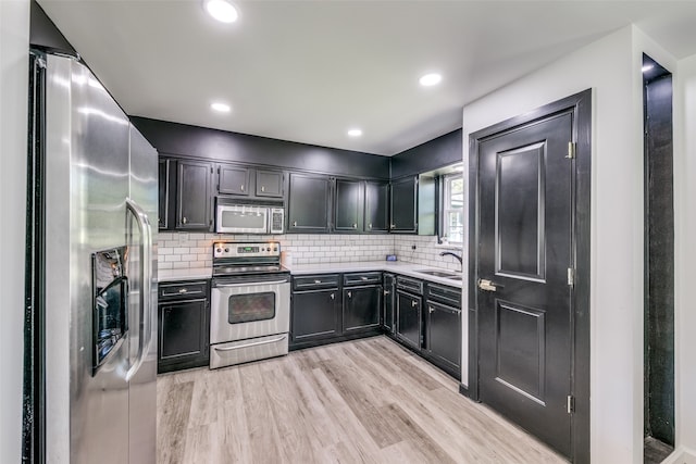 kitchen featuring appliances with stainless steel finishes, sink, light hardwood / wood-style floors, and tasteful backsplash