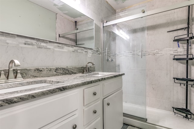 bathroom featuring a shower with shower door, dual vanity, and tile walls