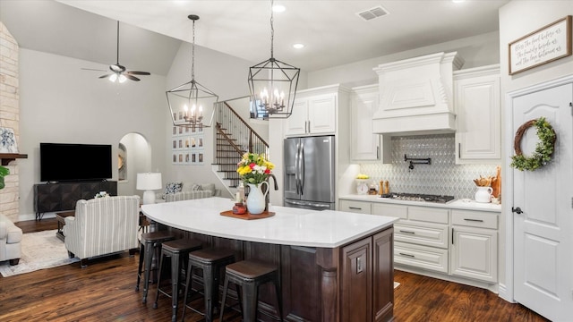 kitchen featuring decorative backsplash, white cabinetry, premium range hood, and stainless steel appliances