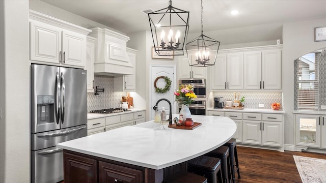 kitchen with a breakfast bar, a center island with sink, white cabinets, and stainless steel appliances